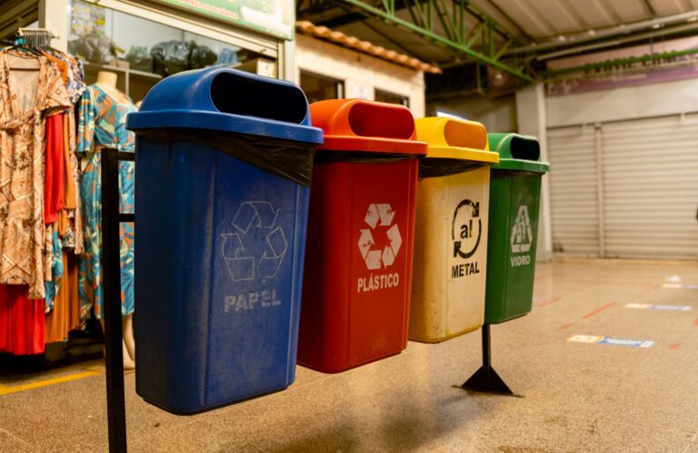 Quatro lixeiras de reciclagem para papel, plástico, metal e vidro em um ambiente interno